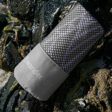 Load image into Gallery viewer, grey towel in pouch nestled among rocks on the shore